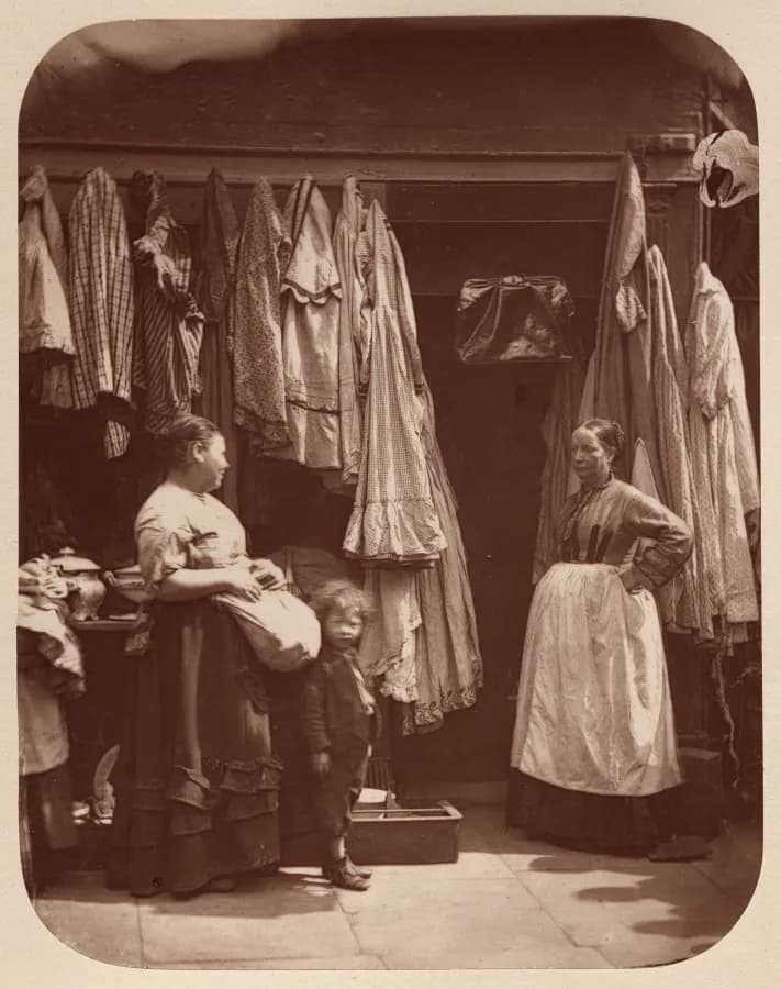 Cultural archive image of “An Old Clothes Shop, Seven Dials”, catalogued as England, 19th century, dating to 1877, associated with England, 19th century. Street Life in London: An Old Clothes Shop, Seven Dials, 1877.