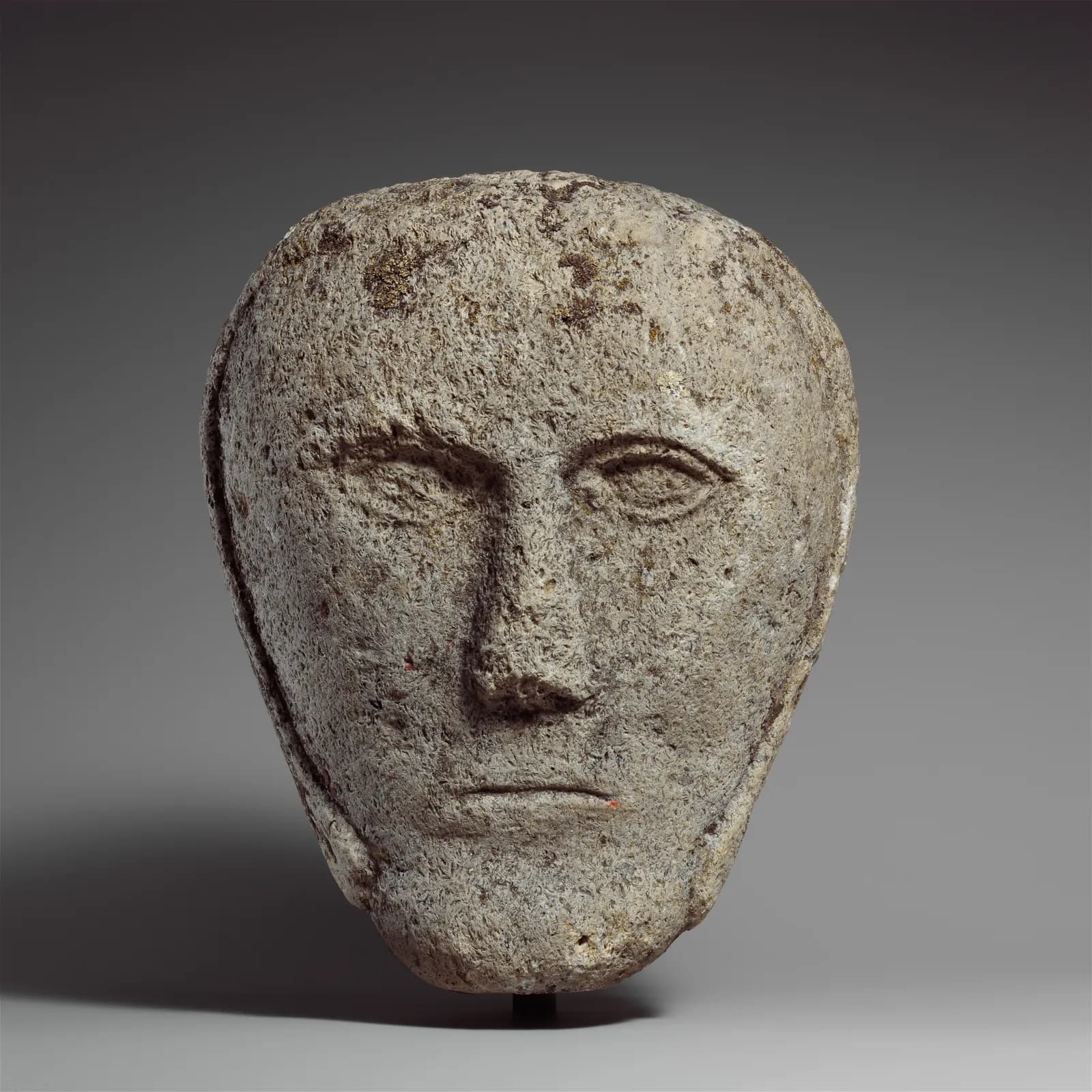 Cultural archive image of “Head of a Man Wearing a Cap or Helmet”, catalogued as Celtic, dating to possibly 2nd–3rd century, associated with probably British Isles. Medium: Fossiliferous limestone.